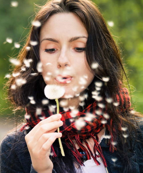 Girl blowing on white dandelion in the forest