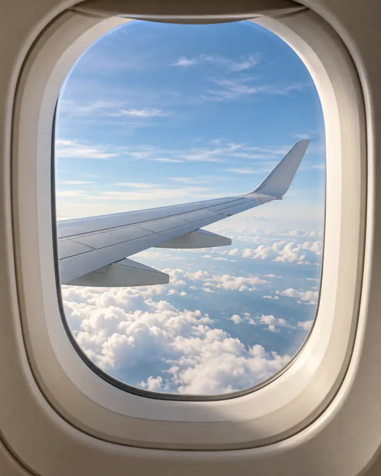 Flyvindue med udsigt til en flyvinge og skyer